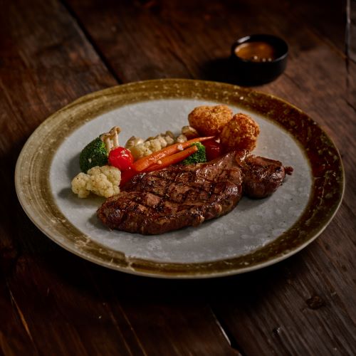 Thai beef sirloin steak with grilled vegetables and potatoes, served with pepper sauce.