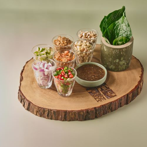 A platter of Miang Kham Chaplu leaves wrap with a mix of herbal ingredients, served with homemade coconut flake sauce.